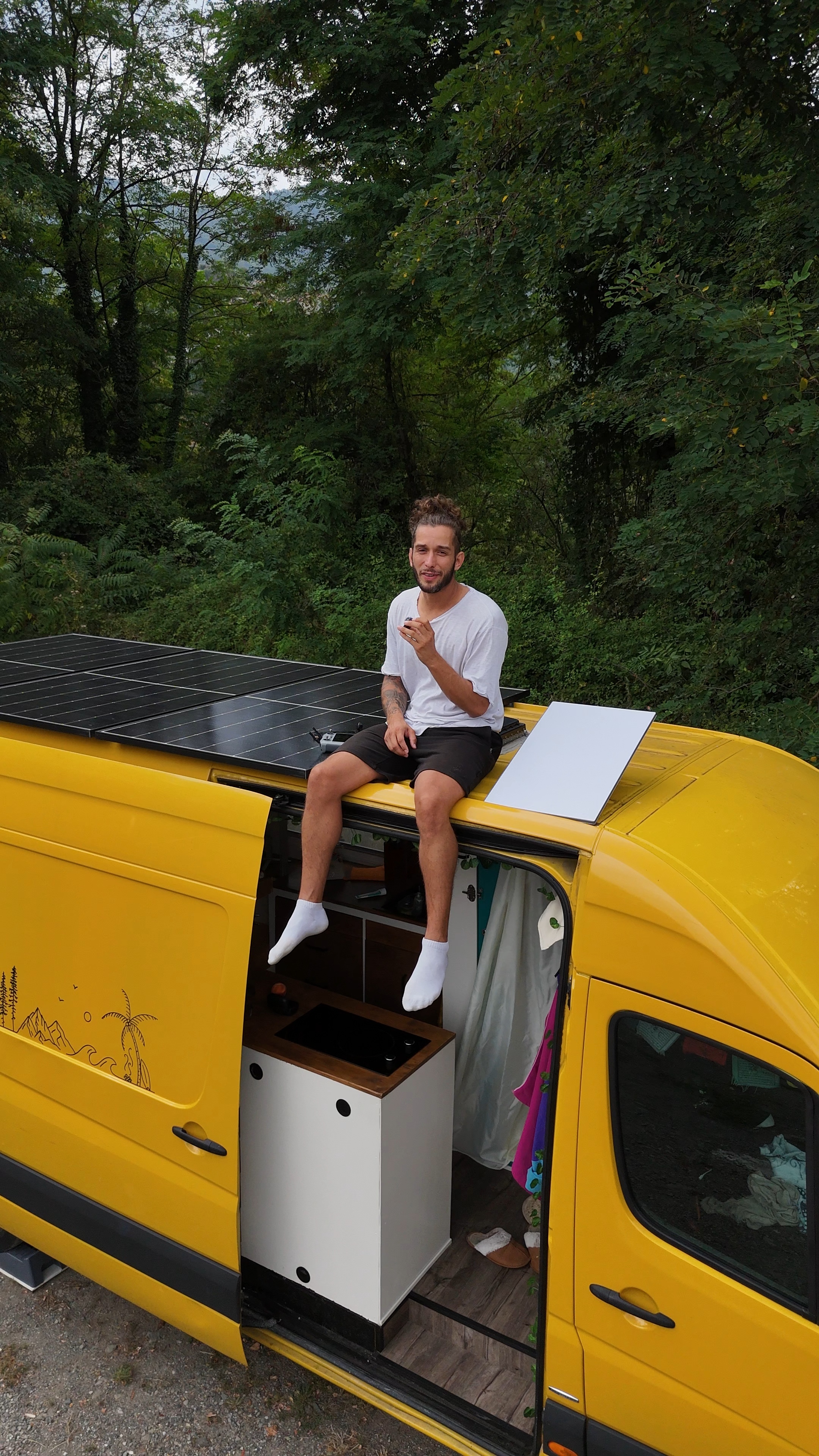 Gaël assis sur le toit du van près des panneaux solaires