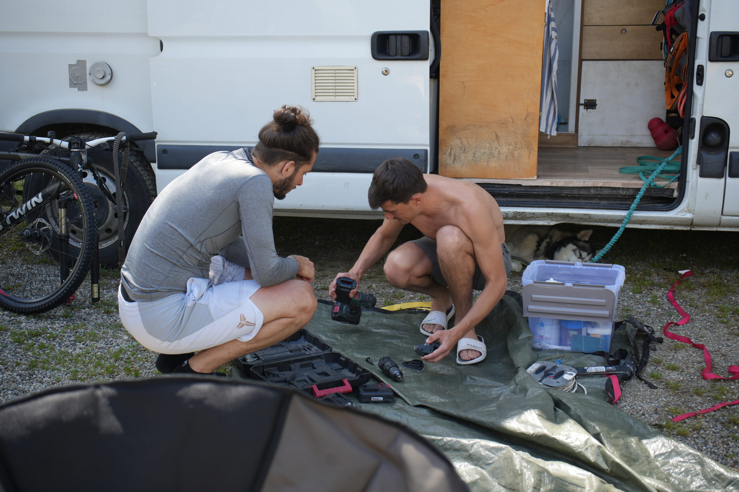 Gaël aide un voyageur devant un van aménagé